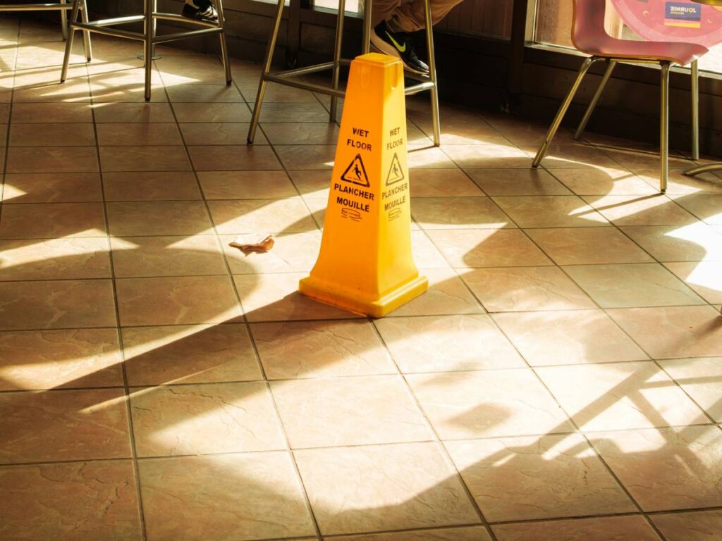 A yellow wet floor sign on tiled floor
