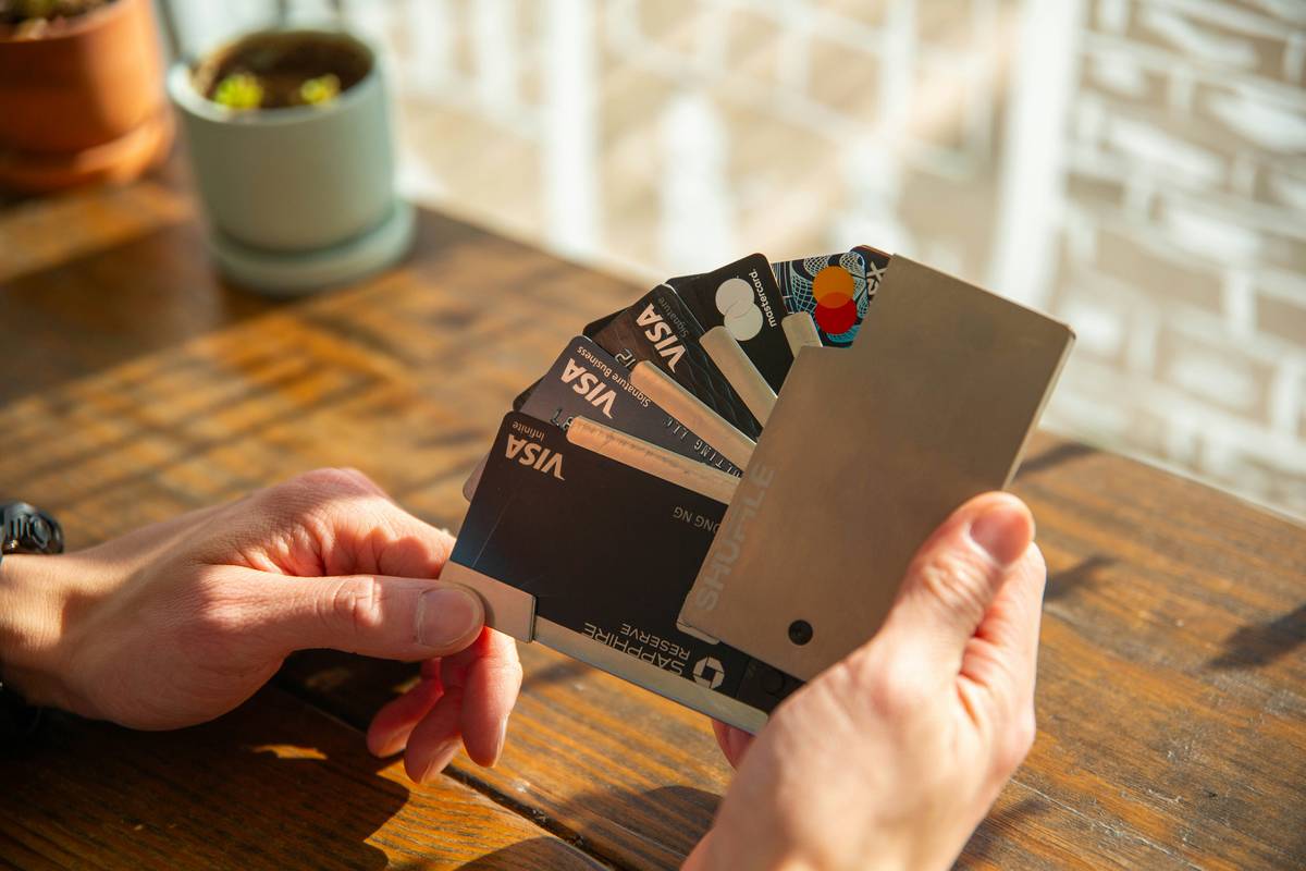Man reviewing bills next to a polluted backyard, holding a pollution cleanup credit card